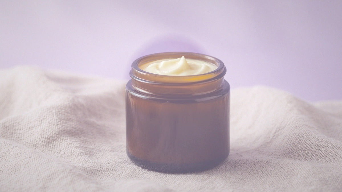 Amber jar of tallow balm on soft linen with lavender light