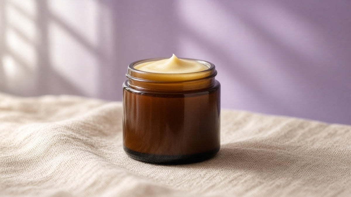 Single amber jar of handmade tallow balm on linen with a soft lavender wash